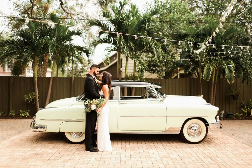 Wedding couple kissing near getaway car